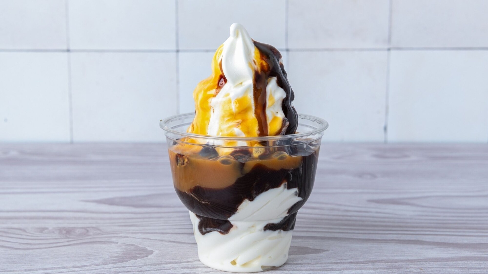 Soft serve sundae with hot fudge and caramel in a clear cup